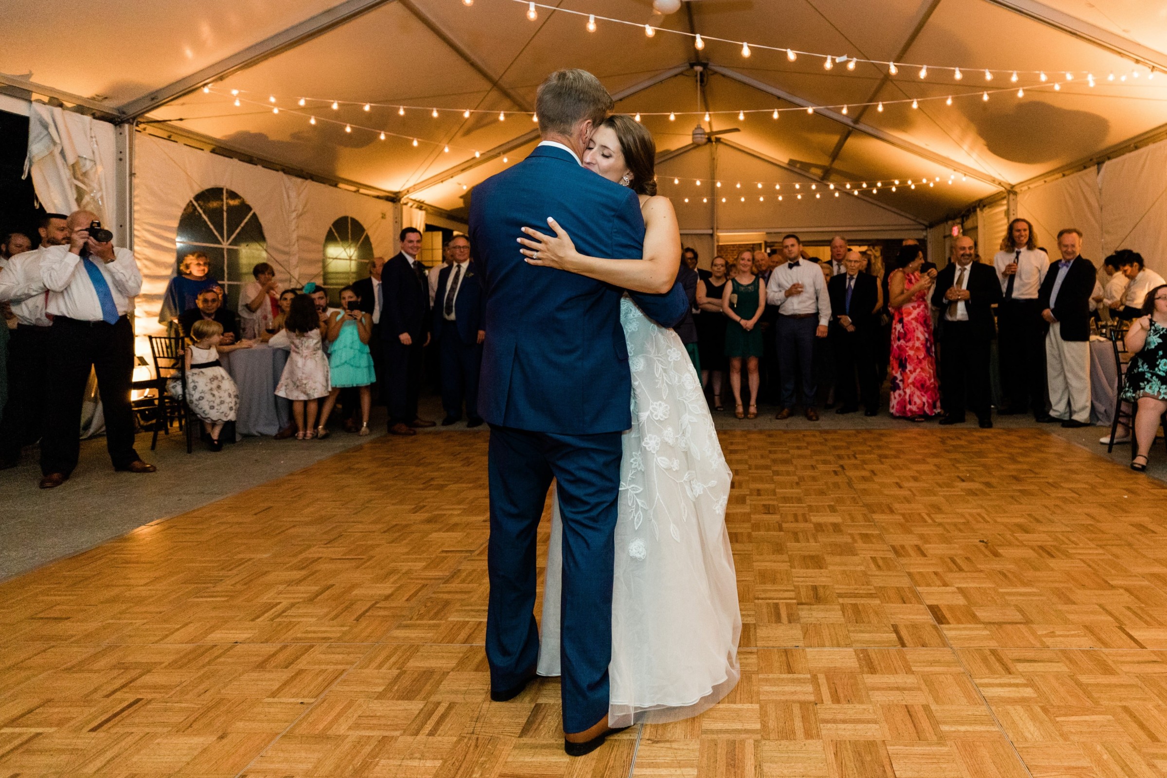 Bride and groom share their first dance under glowing string lights at Elm Bank wedding.