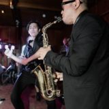 Saxophonist and guitarist performing live jazz in an intimate indoor venue.
