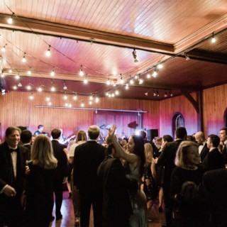 Guests dancing under string lights at an elegant rustic barn wedding in Shelburne Farms, Vermont.