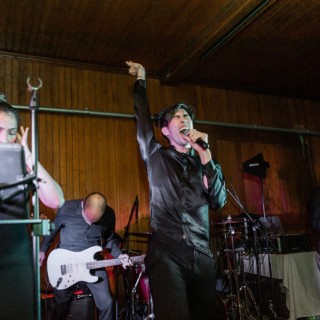 Energetic live band performing on stage with passionate singer and musicians in warm lighting.