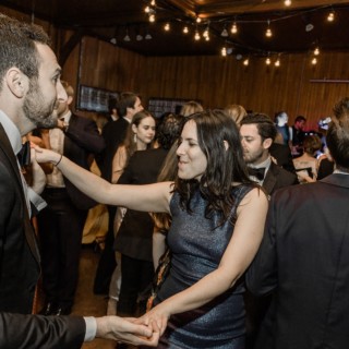 Elegant indoor wedding reception at Shelburne Farms with guests dancing under warm string lights.