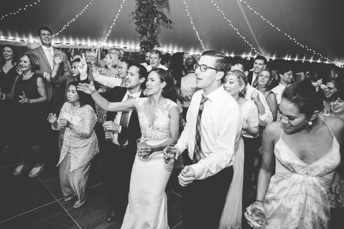 Bride and groom dancing joyfully under twinkling lights at Twin Lake Village wedding reception.