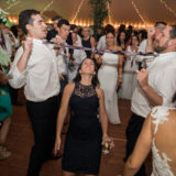 Guests laugh and dance under string lights during a joyful Twin Lake Village wedding celebration.