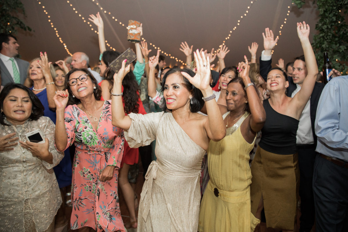 Guests dancing joyfully under glowing string lights at an elegant Twin Lake Village wedding celebration.