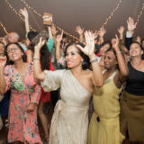 Guests dancing joyfully under glowing string lights at an elegant Twin Lake Village wedding celebration.