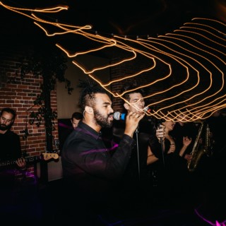 Passionate live band performance with soulful vocalist and warm glowing lights in an intimate venue.