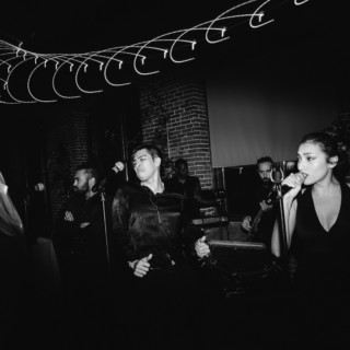 Black and white band performance with passionate singer in intimate brick music venue.