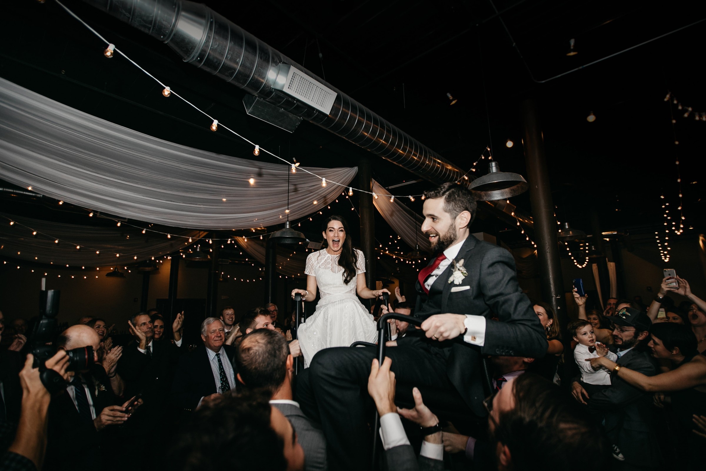 Bride and groom lifted during joyful Hora dance at Rivermill Dover wedding celebration.