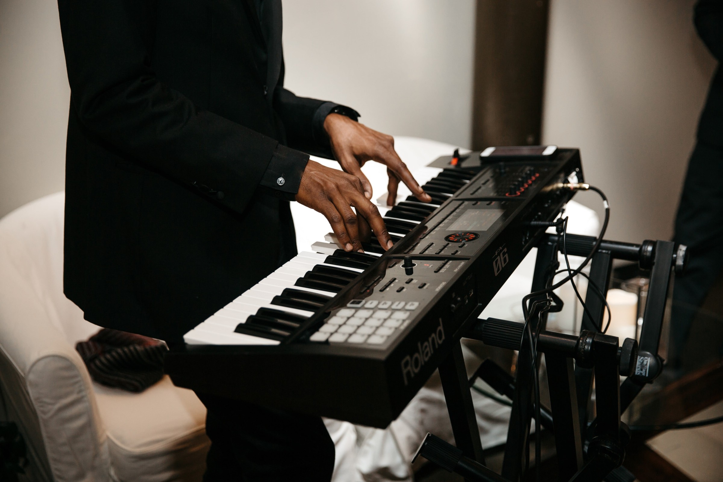 Professional musician performing on a Roland keyboard in an elegant, softly lit setting.