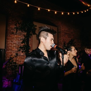 Energetic live band performing at Rivermill Dover NH wedding under warm lights and rustic brick walls.