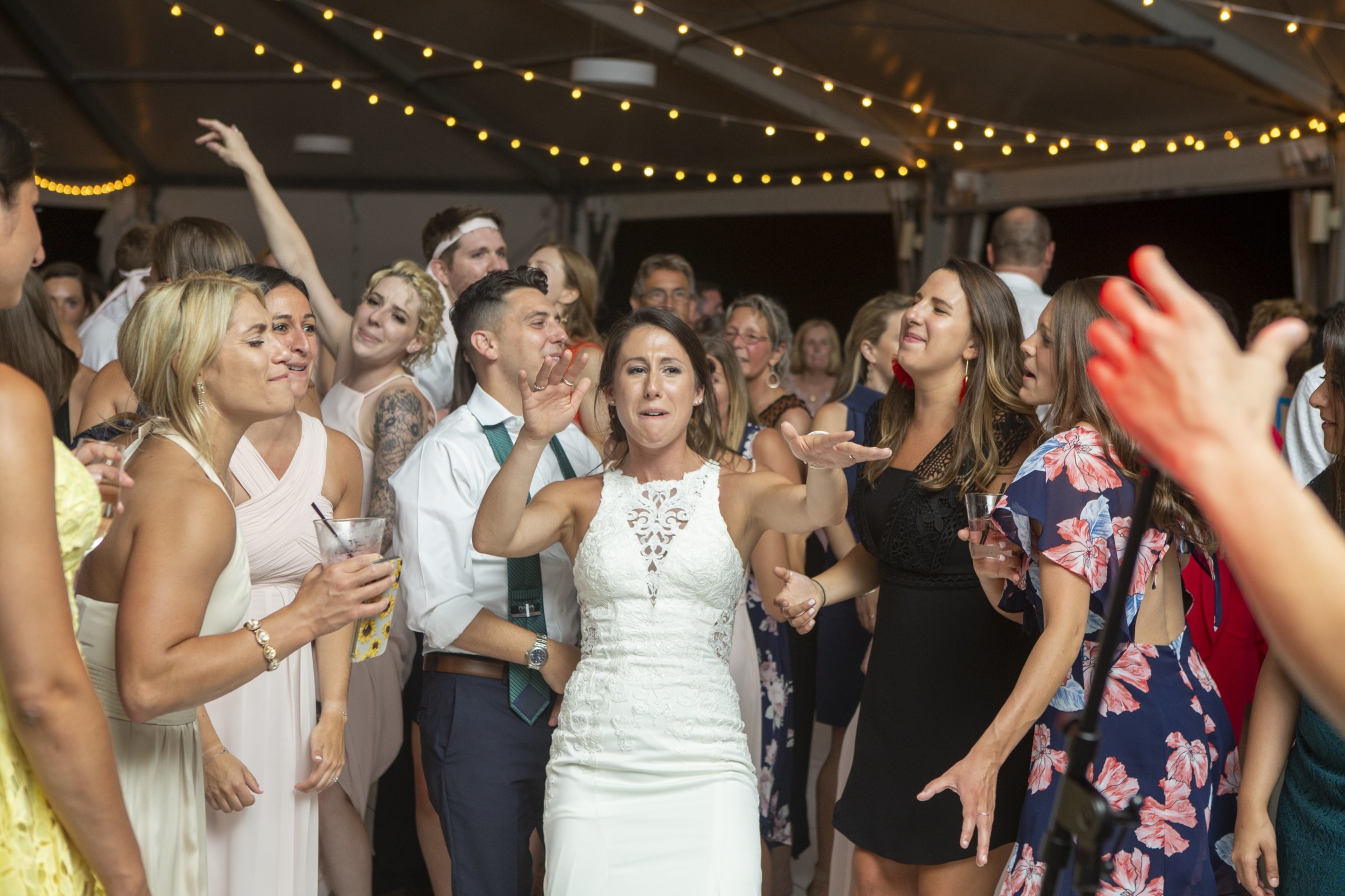 Bride dancing joyfully with guests under string lights at Granite Links Golf Club wedding.