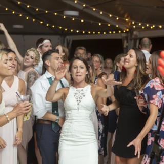 Bride dancing joyfully with guests under string lights at Granite Links Golf Club wedding.