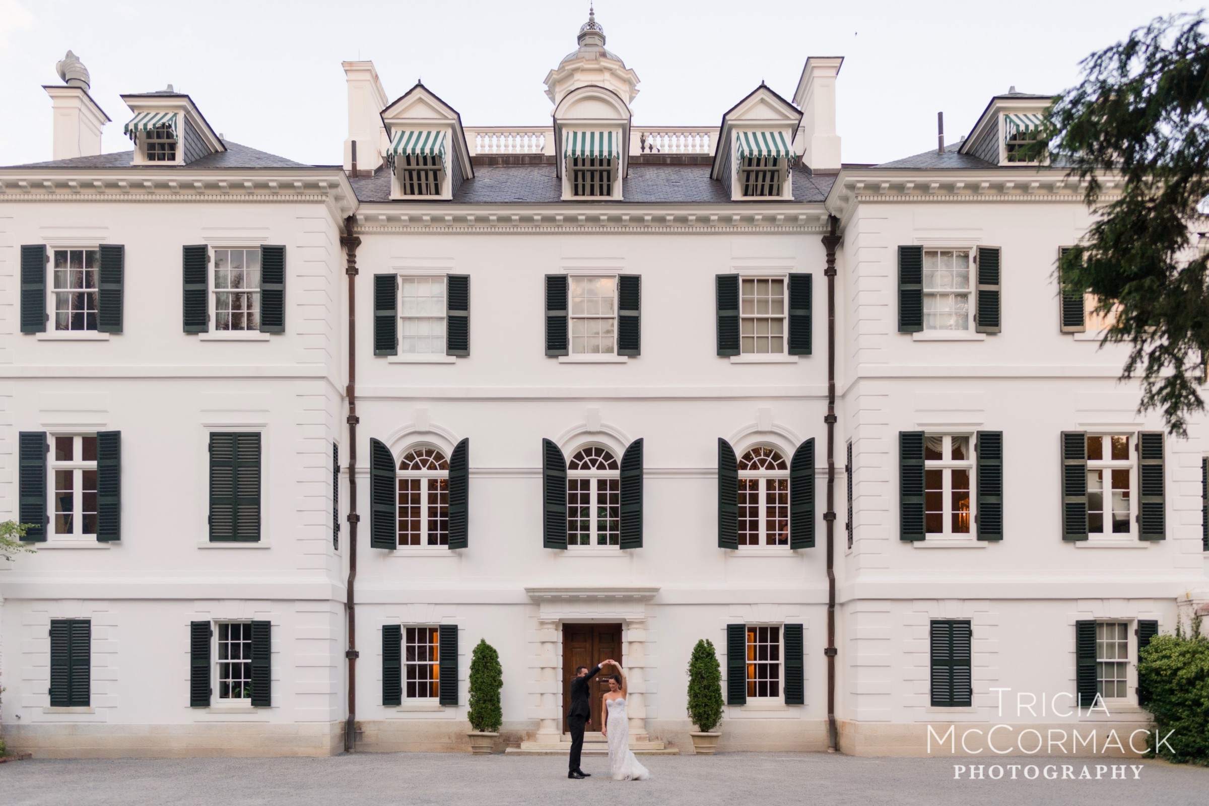 Bride and groom dancing before the grand white facade of The Mount Mansion in Lenox, Massachusetts.