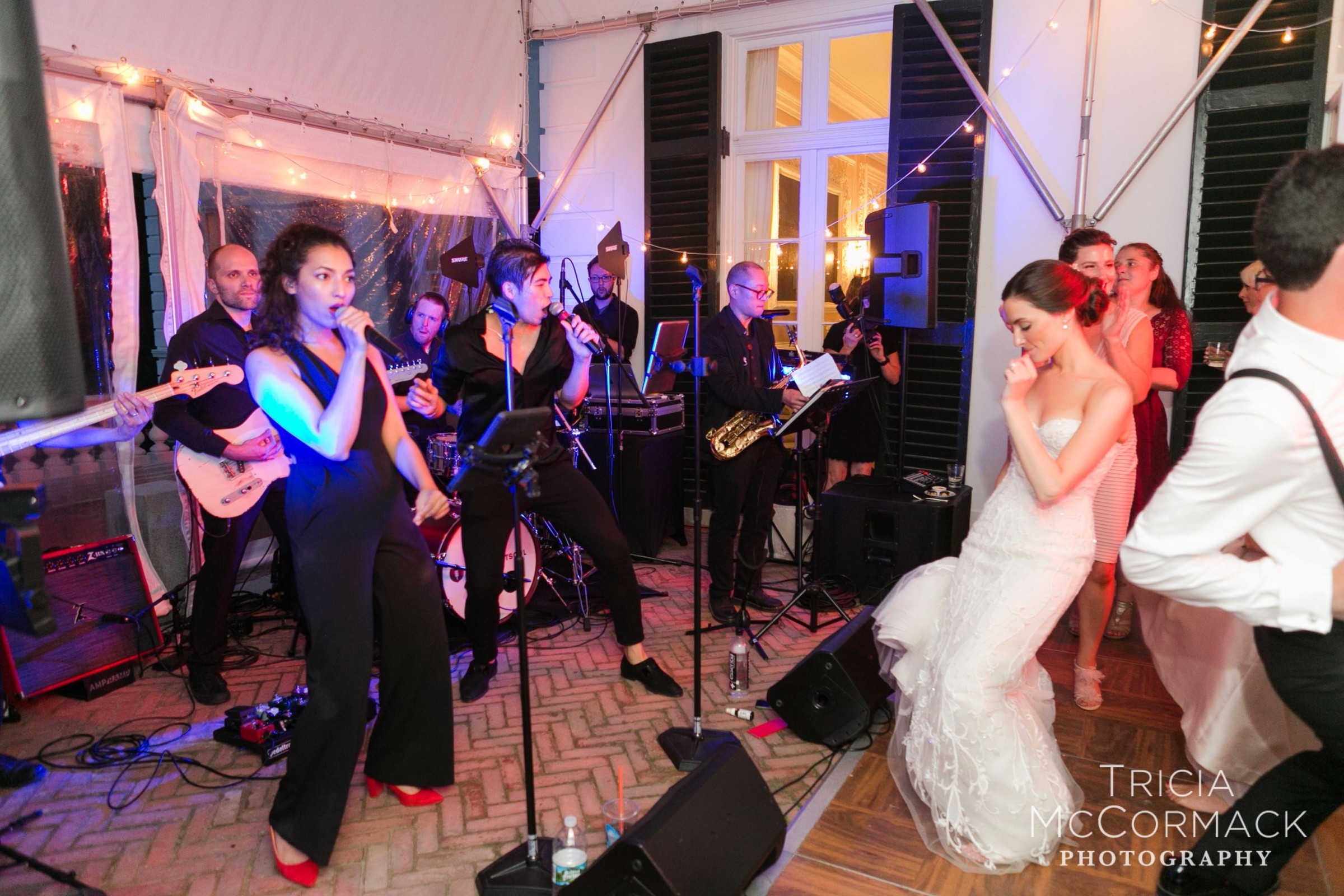 Bride dancing joyfully to live band under romantic string lights at elegant Lenox wedding.