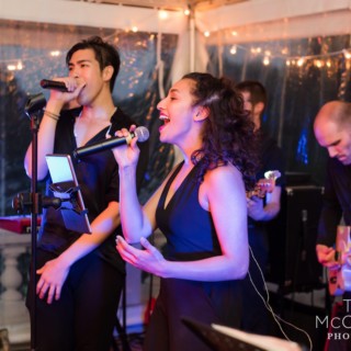 Energetic wedding band performing under warm string lights in Lenox, Massachusetts.