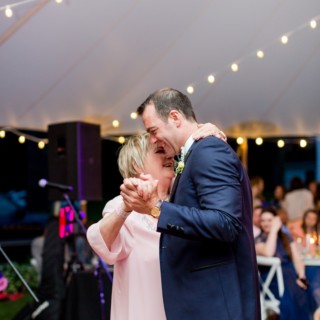 Groom shares emotional mother-son dance under glowing string lights at Twin Lakes Village wedding.