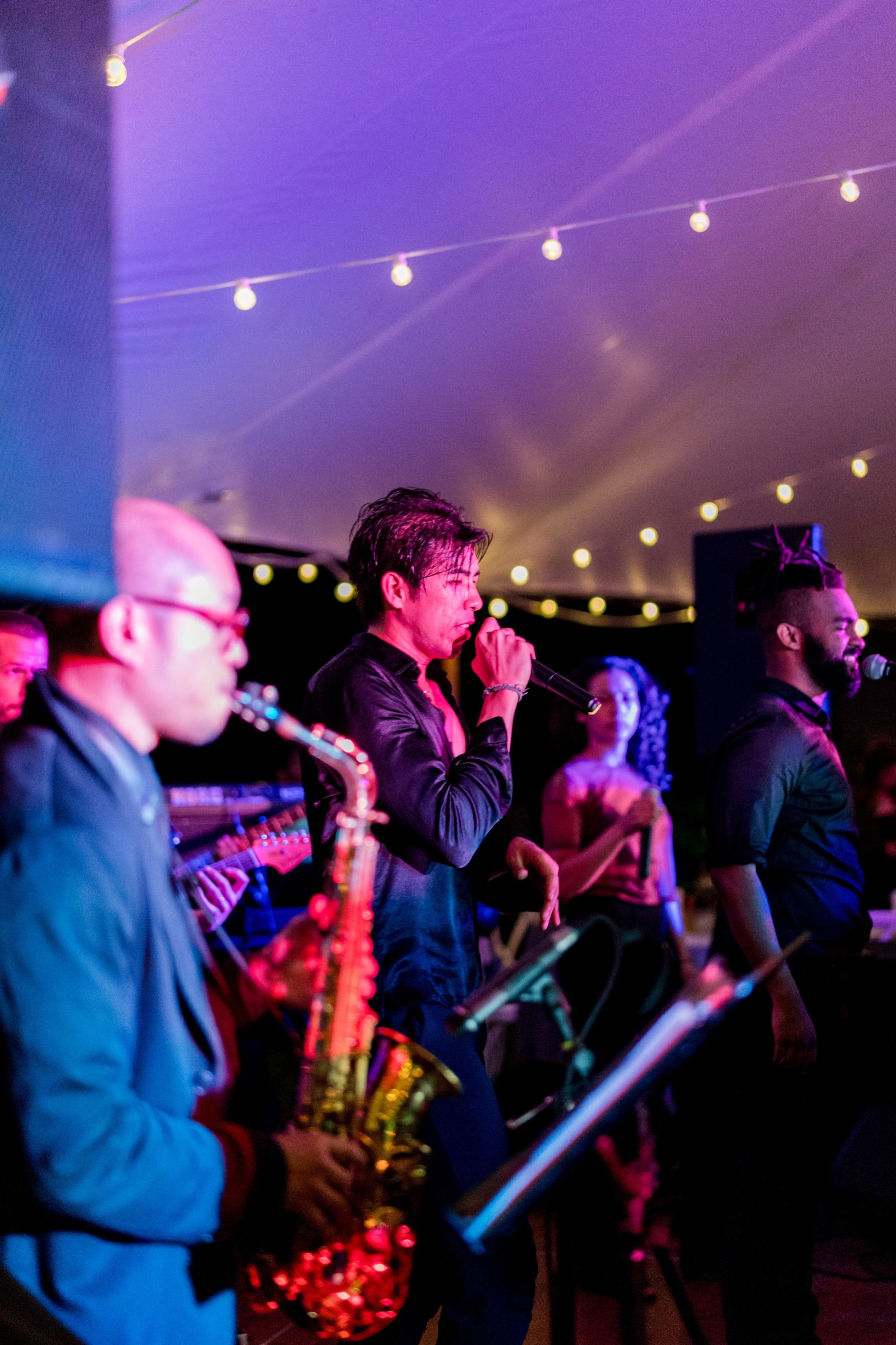 Live wedding band performing under warm string lights in New London, New Hampshire.