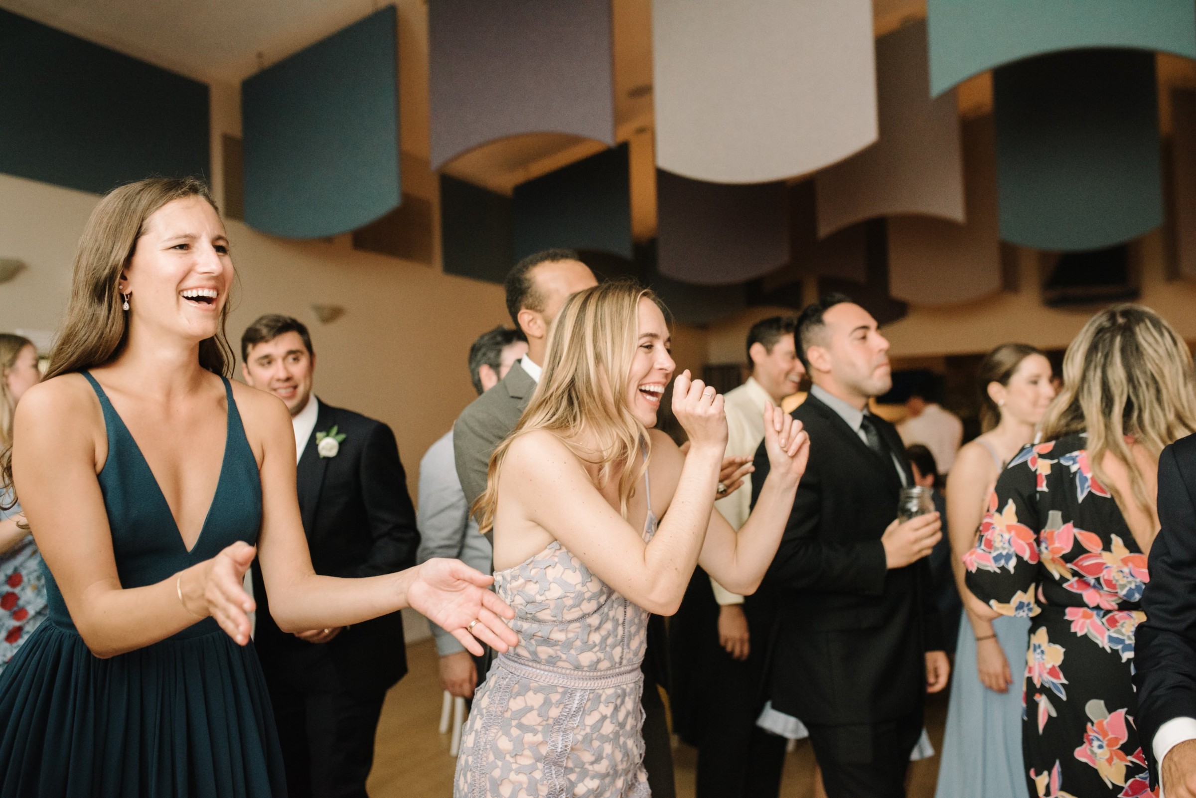 Guests laughing and cheering during a lively wedding reception at West Dennis Yacht Club.