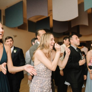 Guests laughing and cheering during a lively wedding reception at West Dennis Yacht Club.