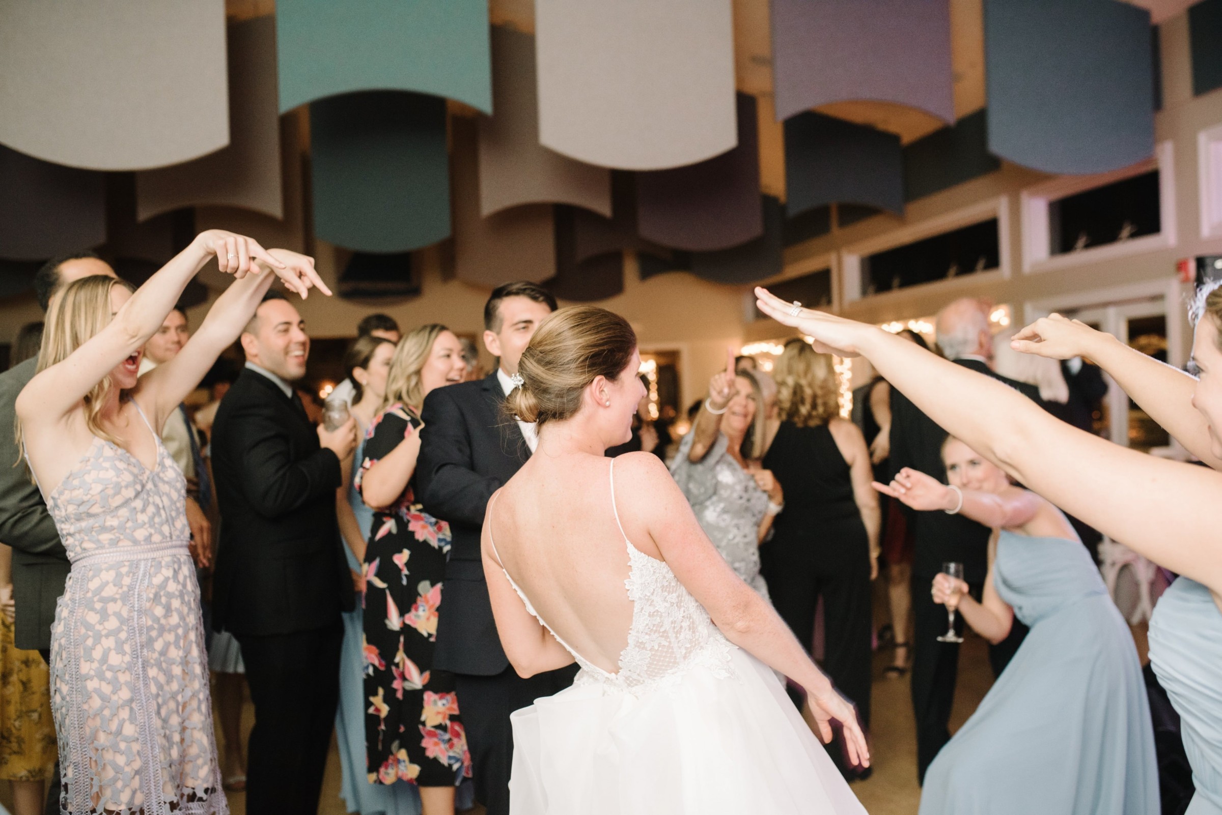 Bride dancing joyfully with guests at West Dennis Yacht Club wedding celebration.