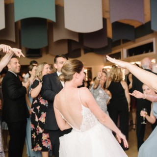 Bride dancing joyfully with guests at West Dennis Yacht Club wedding celebration.