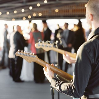 Electric guitarist performing at elegant wedding reception under warm string lights.
