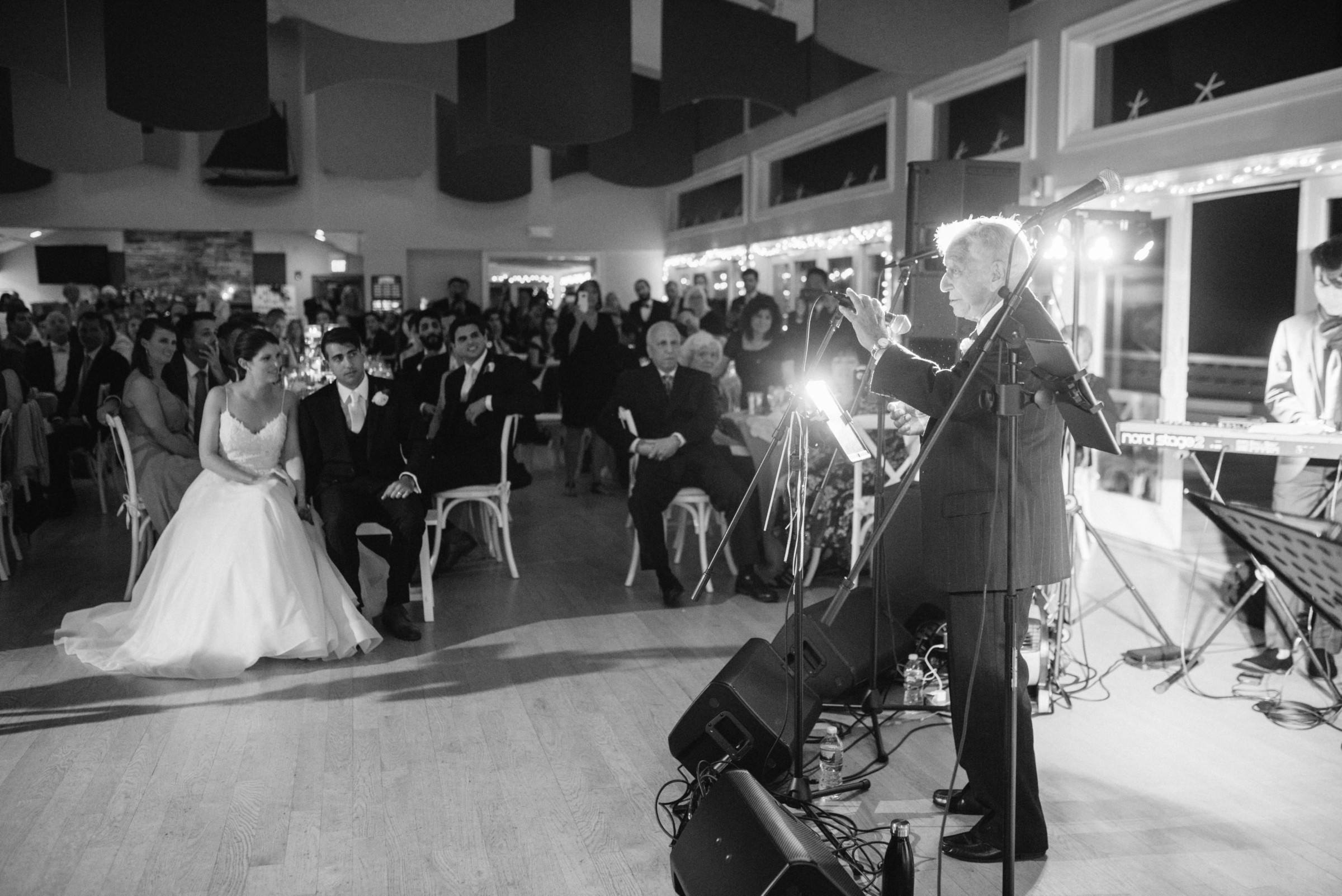 Elderly man giving emotional wedding speech to bride and groom at West Dennis Yacht Club.
