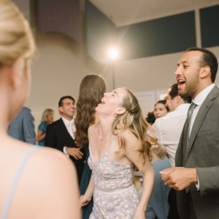 Laughing wedding guests dancing at West Dennis Yacht Club reception in warm, joyful atmosphere.