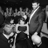 Bride laughing as guests lift her during joyful black-and-white wedding hora at Newport Marriott.
