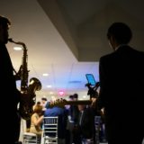 Silhouetted jazz duo performing at elegant Newport wedding reception with warm ambient lighting.