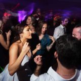 Bride dancing joyfully with guests under colorful lights at Newport Marriott wedding reception.