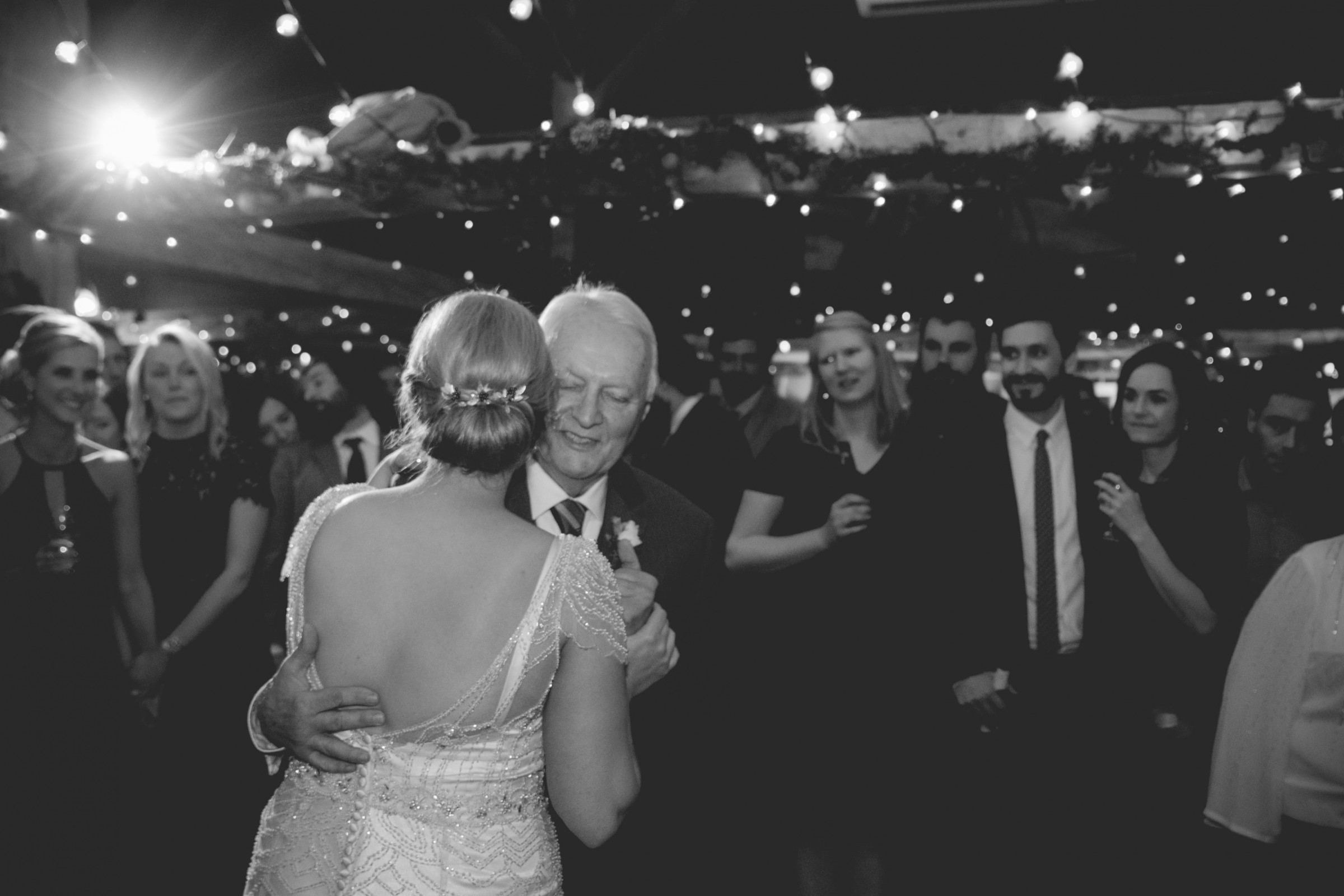 Bride and father share emotional dance under glowing string lights at Stone Mountain wedding.