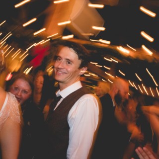Smiling wedding guest dancing under warm golden lights at Stone Mountain Arts Center in Maine.