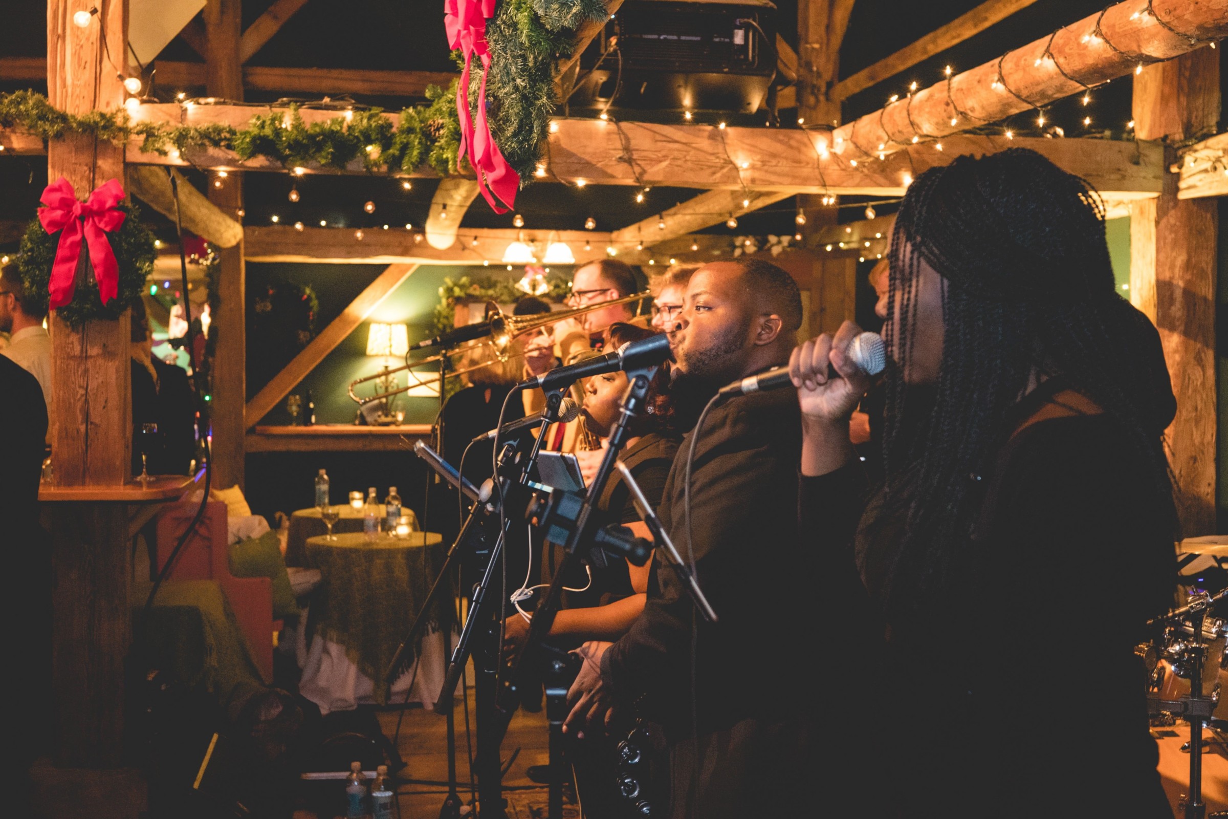 Live holiday band performing at rustic Stone Mountain Arts Center in warm festive lighting.