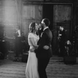 Bride and groom share a joyful first dance in a rustic barn wedding setting.