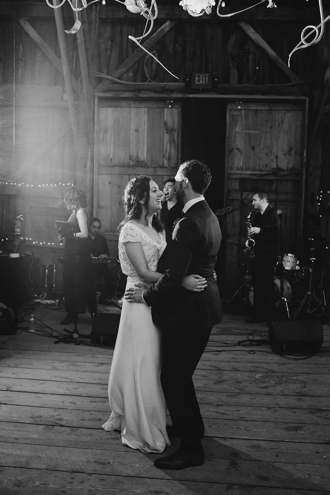 Bride and groom share a joyful first dance in a rustic barn wedding setting.