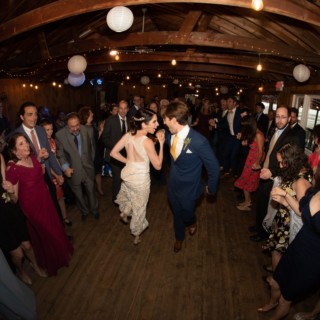 Bride and groom dancing joyfully at rustic fairy-lit wedding in Wellfleet, Massachusetts.