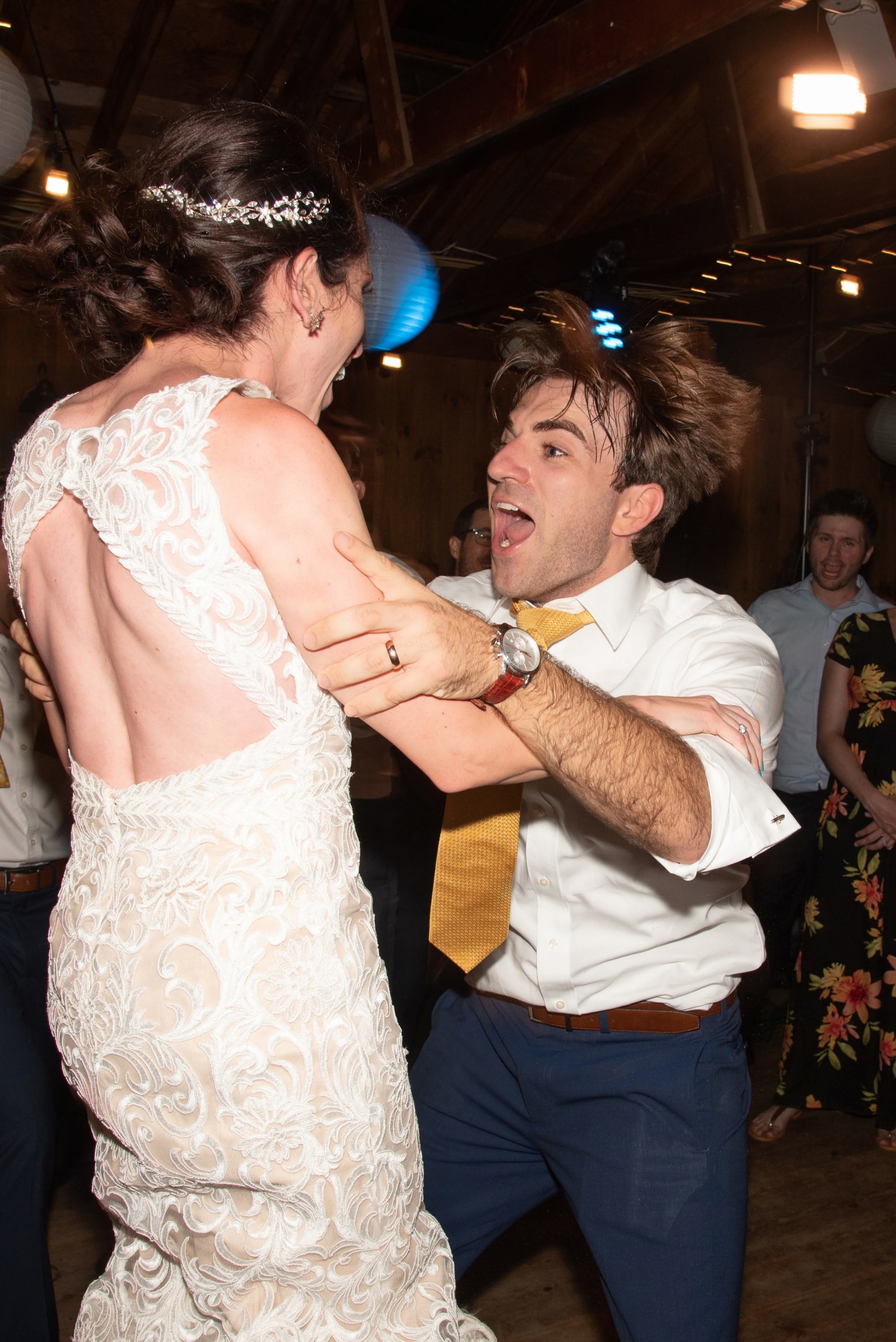 Bride and groom joyfully dancing under string lights at rustic Chequessett Yacht Club wedding.