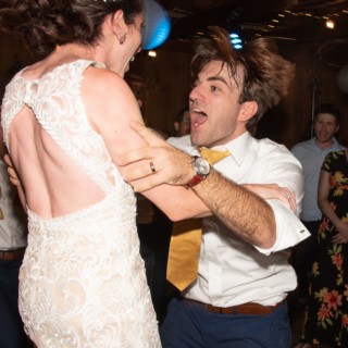 Bride and groom joyfully dancing under string lights at rustic Chequessett Yacht Club wedding.