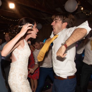 Bride and groom dancing joyfully under string lights at Chequessett Yacht & Country Club wedding.