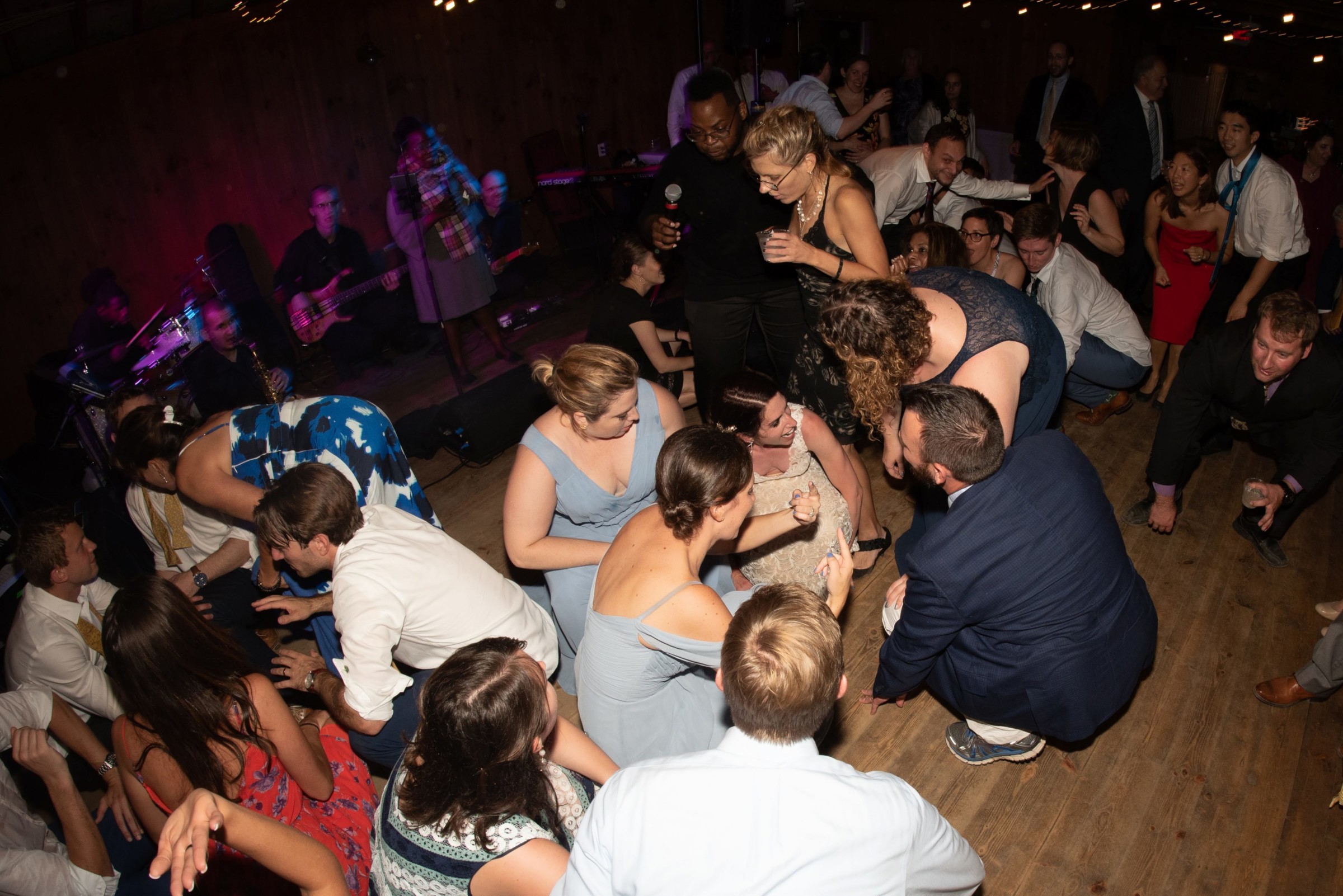 Guests dancing joyfully at rustic Wellfleet wedding with live band and warm string lights.
