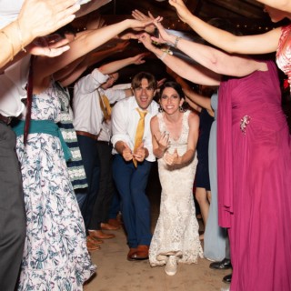 Bride and groom dancing through guests’ arm tunnel at joyful Chequessett Club wedding celebration.