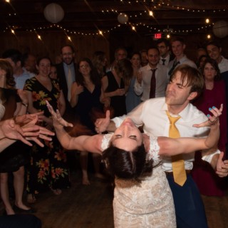 Bride and groom dancing joyfully under string lights at Chequessett Yacht Club wedding.