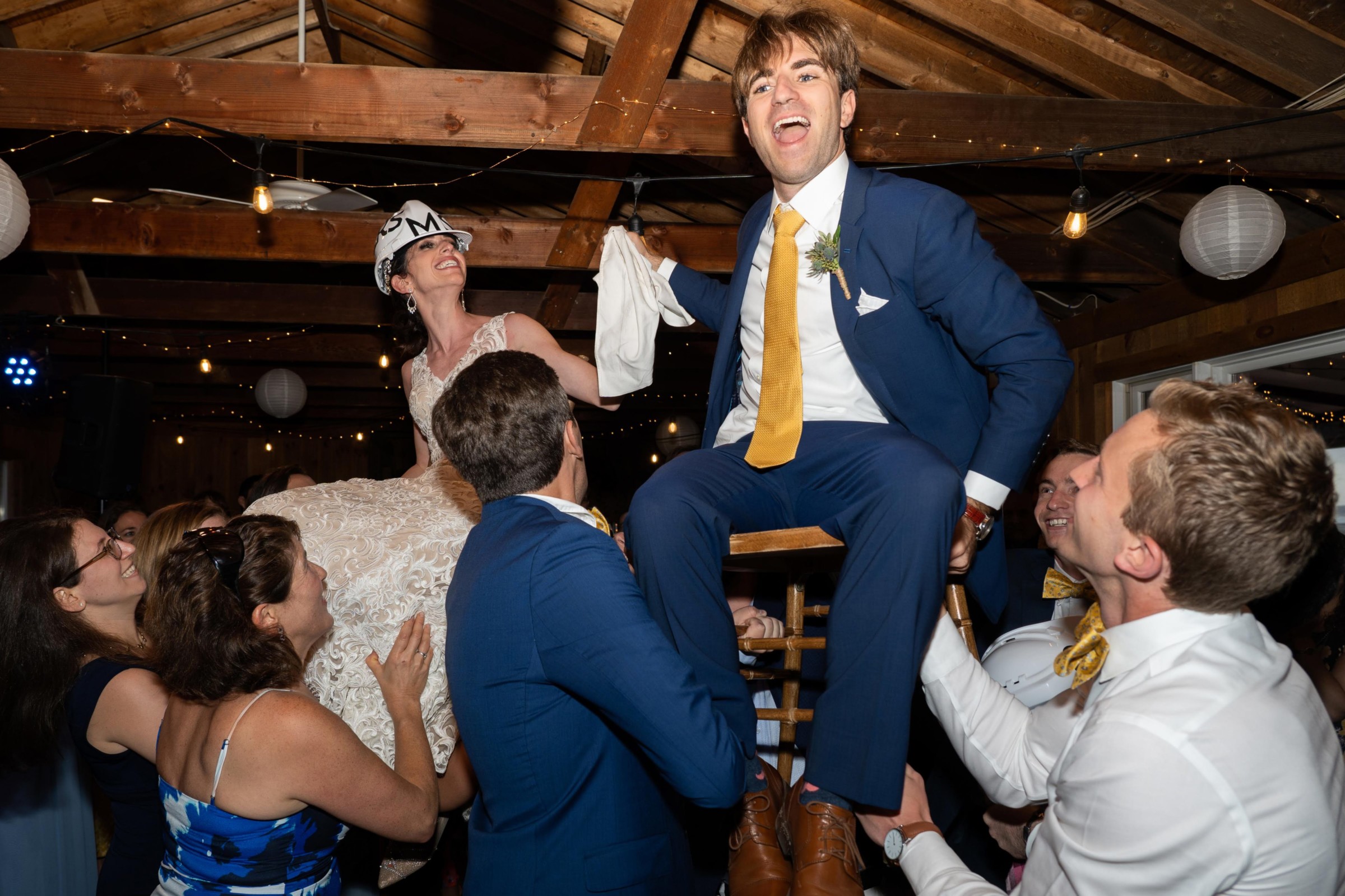 Bride and groom lifted during joyful Hora dance at Chequessett Yacht & Country Club wedding.