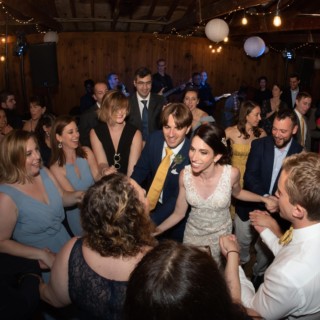Bride and groom dancing joyfully with guests at rustic Chequessett Yacht Club wedding in Wellfleet.
