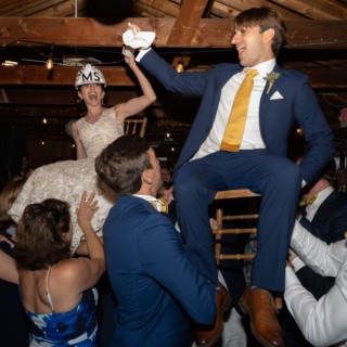 Bride and groom lifted during Hora dance at joyful Chequessett wedding celebration.