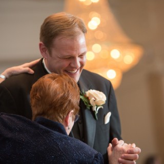 Groom joyfully dances with his mother under warm golden lights at Boston wedding reception.