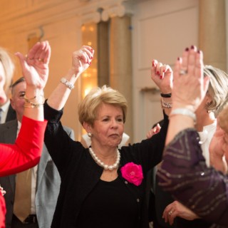 Older guests joyfully dancing at an elegant Boston wedding reception under warm, festive lighting.