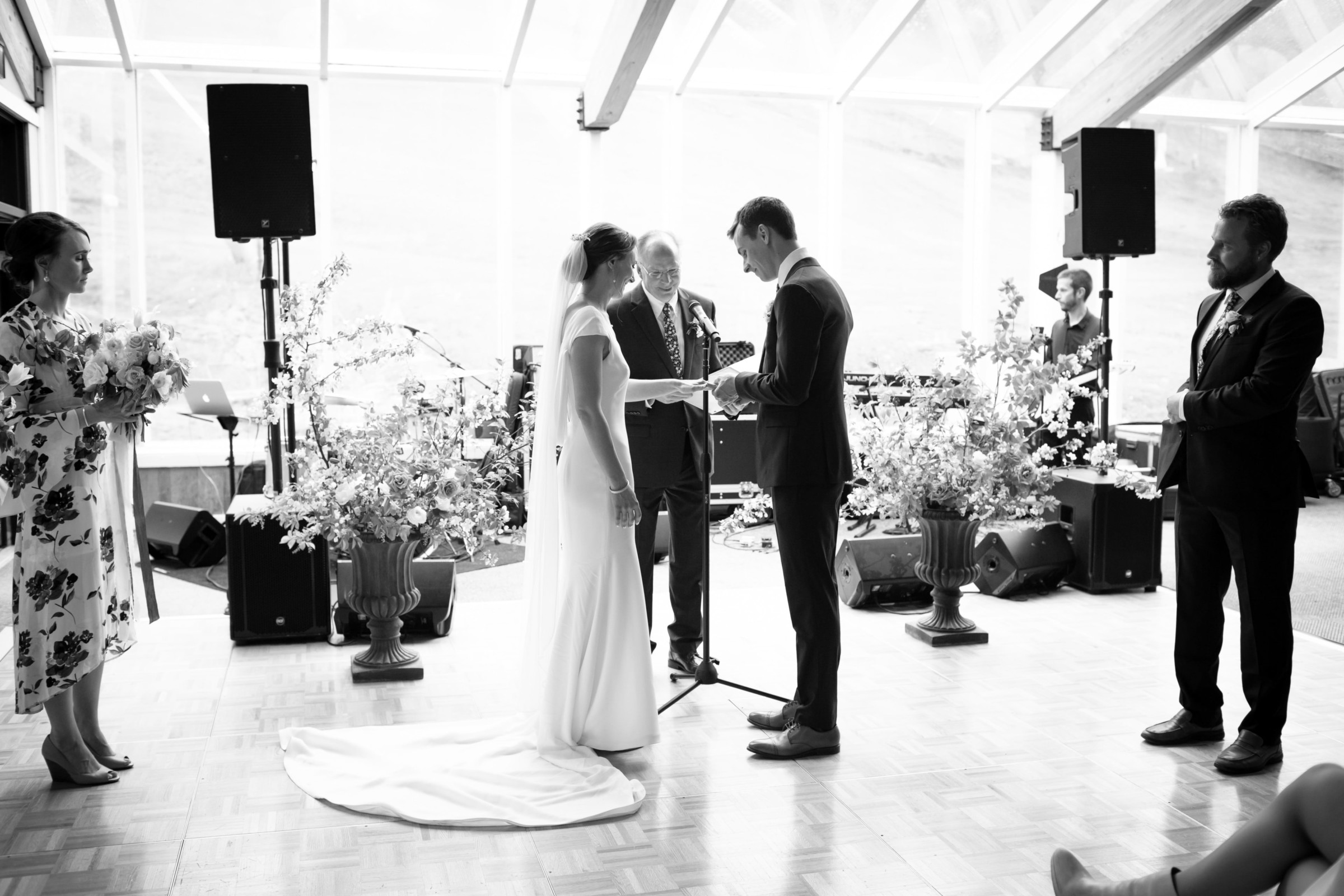 Black and white indoor wedding ceremony in Pomfret Vermont with bride, groom, and floral decor.