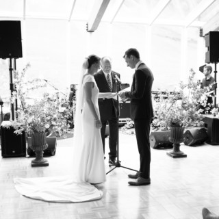 Black and white indoor wedding ceremony in Pomfret Vermont with bride, groom, and floral decor.